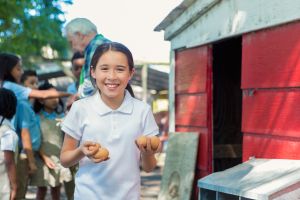Student holding eggs in chicken coop during farm field trip