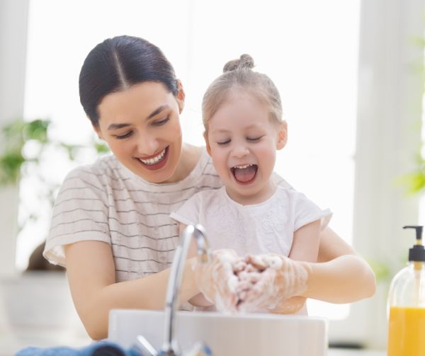 Mother washing hands with daughter