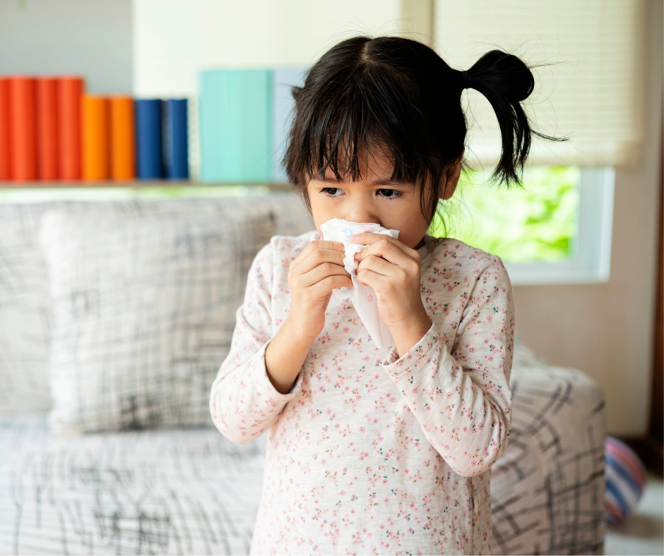 Young girl blowing her nose with a tissue